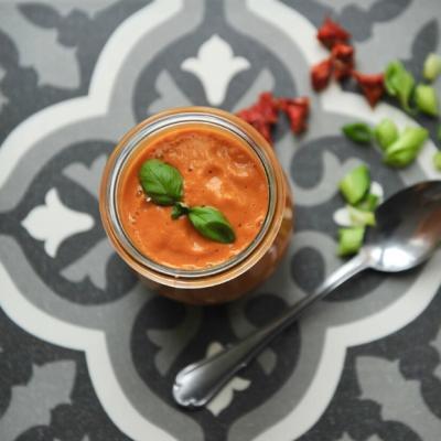 Creamy tomato soup in jar garnished with basil.