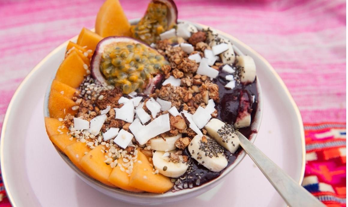Acai bowl recipe with toppings of passion fruit, banana, granola and hemp seeds