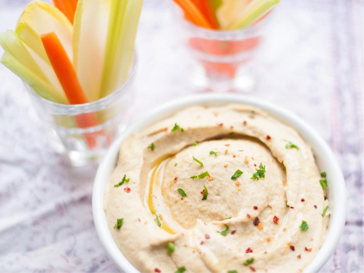 Hummus recipe: bowl filled with hummus and vegetable sticks