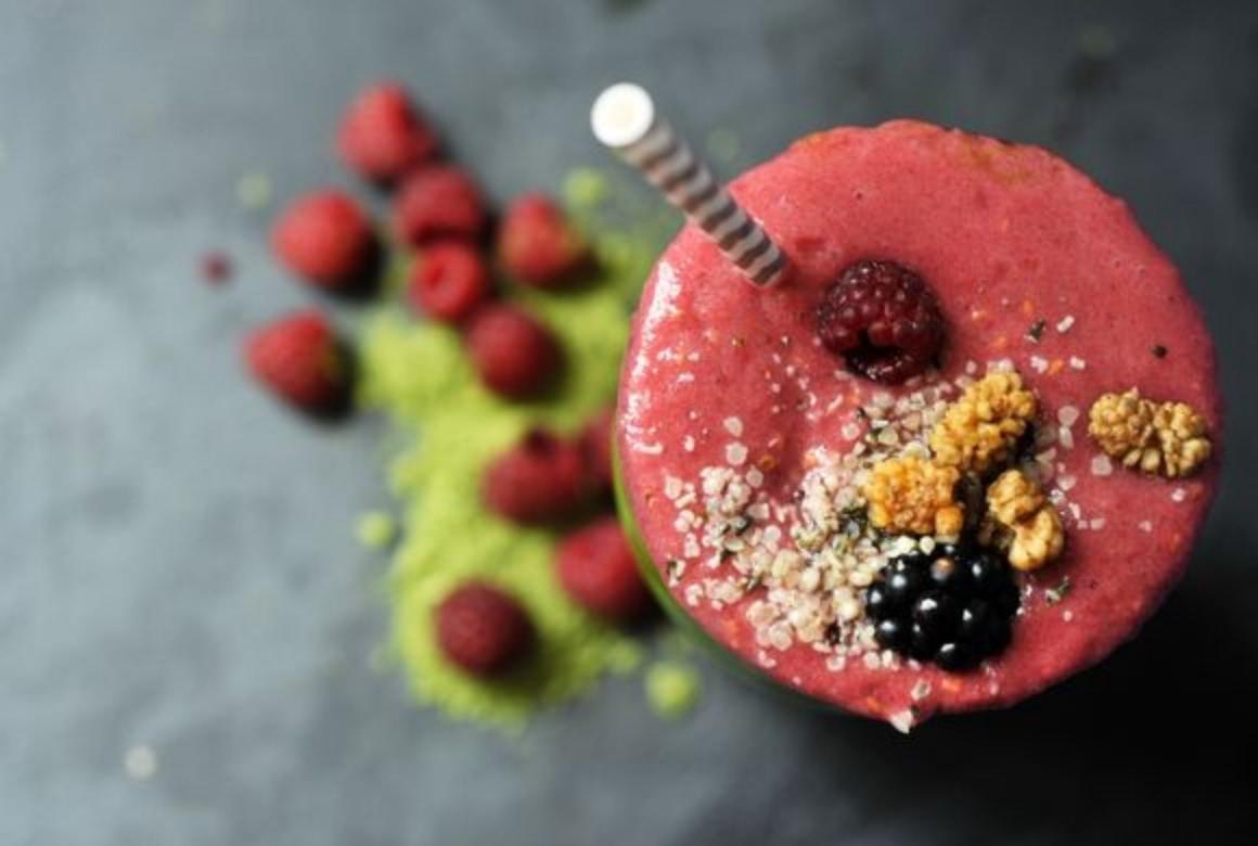 Wheatgrass smoothie with topping of mulberries, raspberry, blackberry and hemp seeds